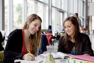 Two students in a library studying in Quebec, Canada with their CAQ and study permit